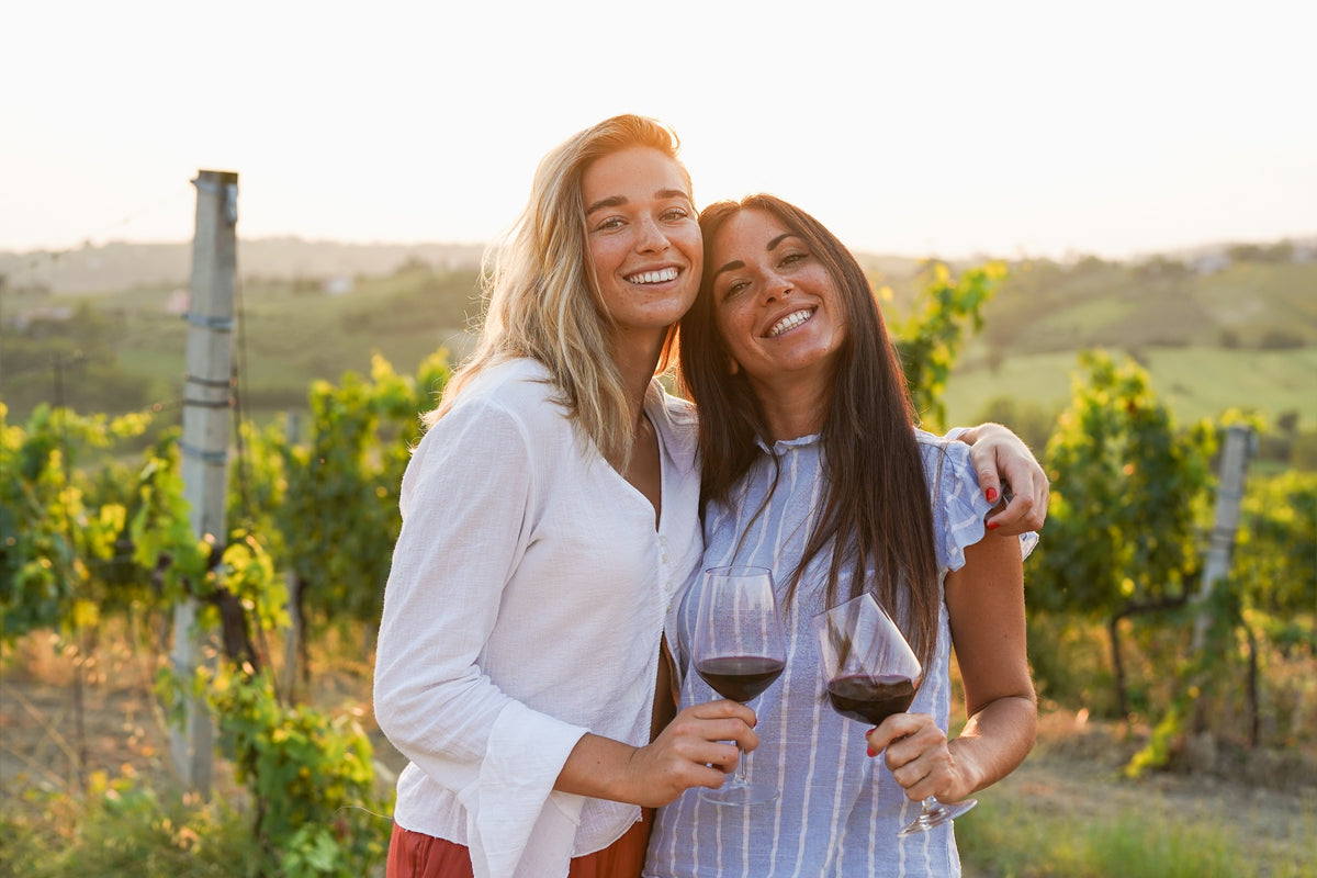Wine tasting experience included with the Southern Highlands Tasting Pass. Two young women looking at the camera with a glass of red wine in their hands.