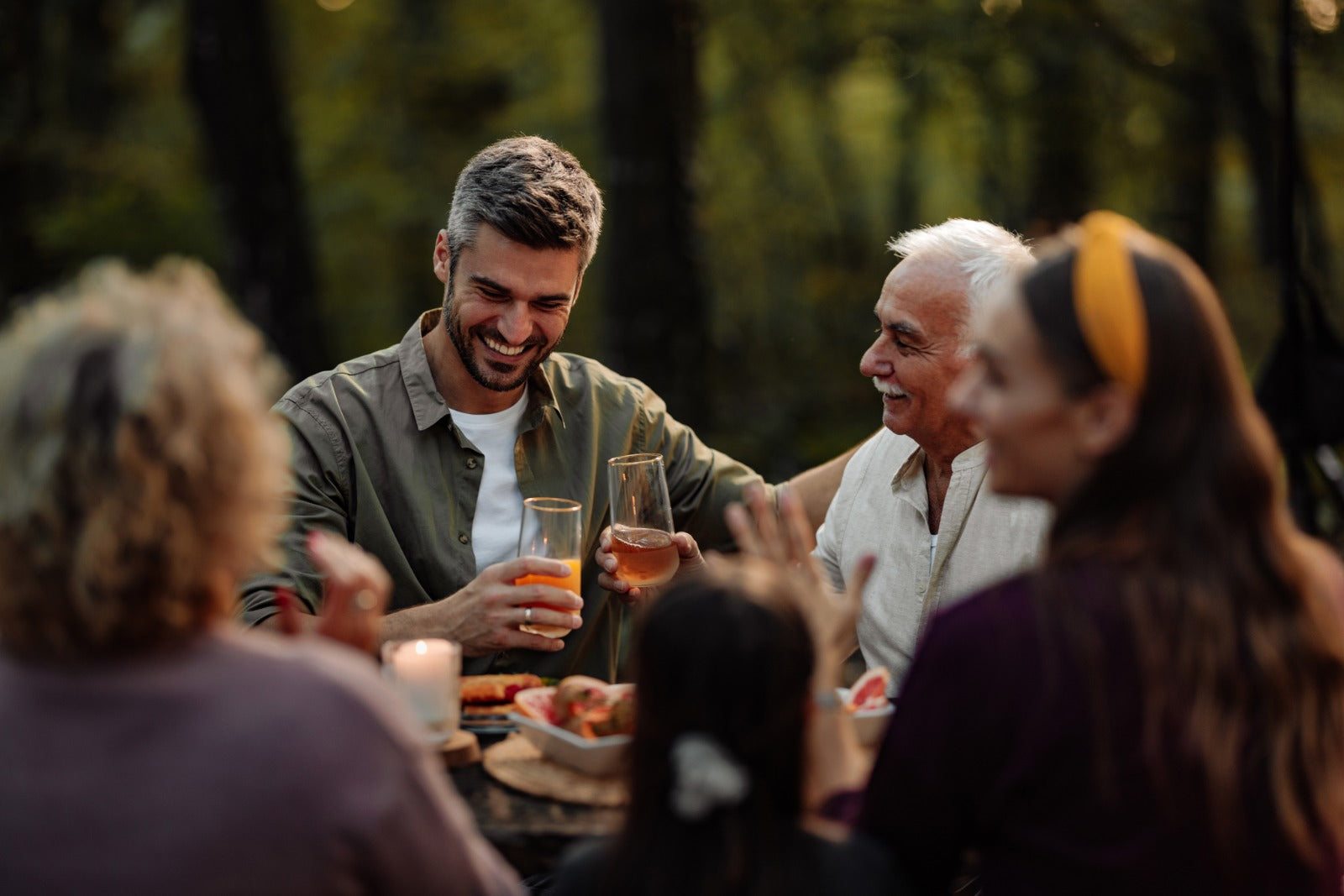 Group of people enjoying a meal outdoors in a forest setting